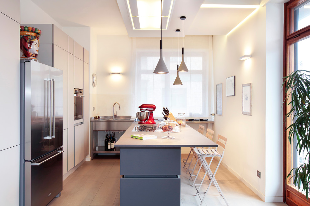 Inspiration for a contemporary l-shaped kitchen in Turin with an integrated sink, flat-panel cabinets, beige cabinets, stainless steel appliances, with island and beige floor.