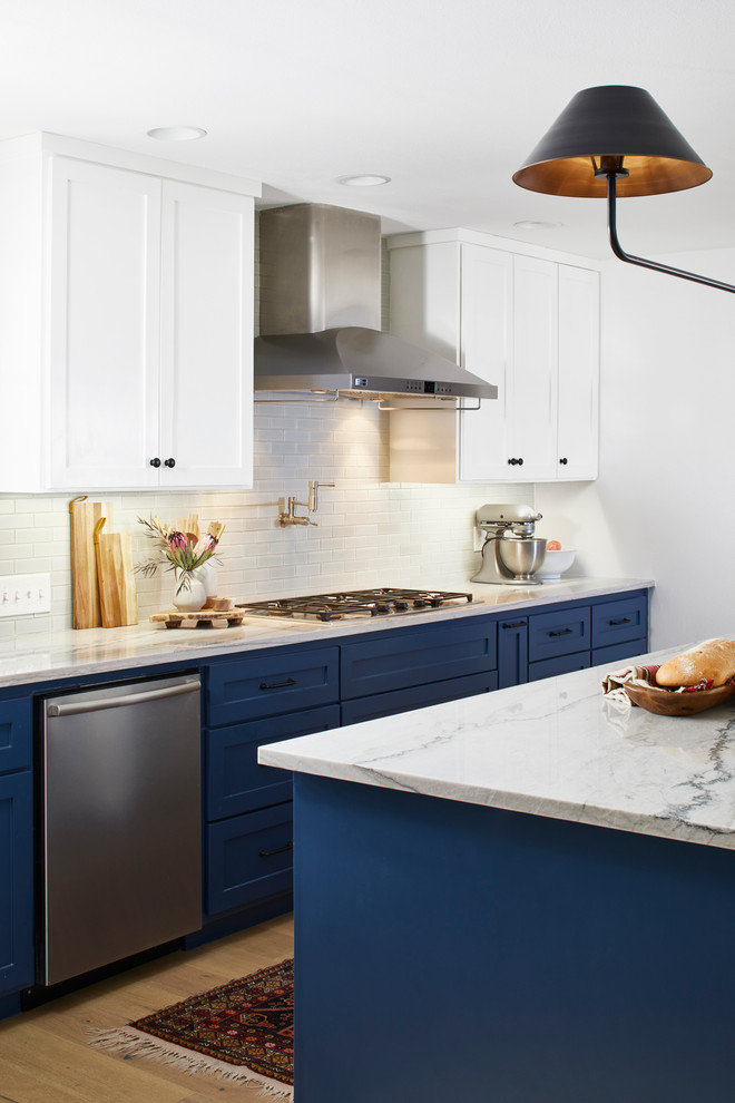Open concept kitchen - large transitional l-shaped light wood floor and beige floor open concept kitchen idea in Austin with an undermount sink, shaker cabinets, blue cabinets, marble countertops, white backsplash, subway tile backsplash, stainless steel appliances and an island
