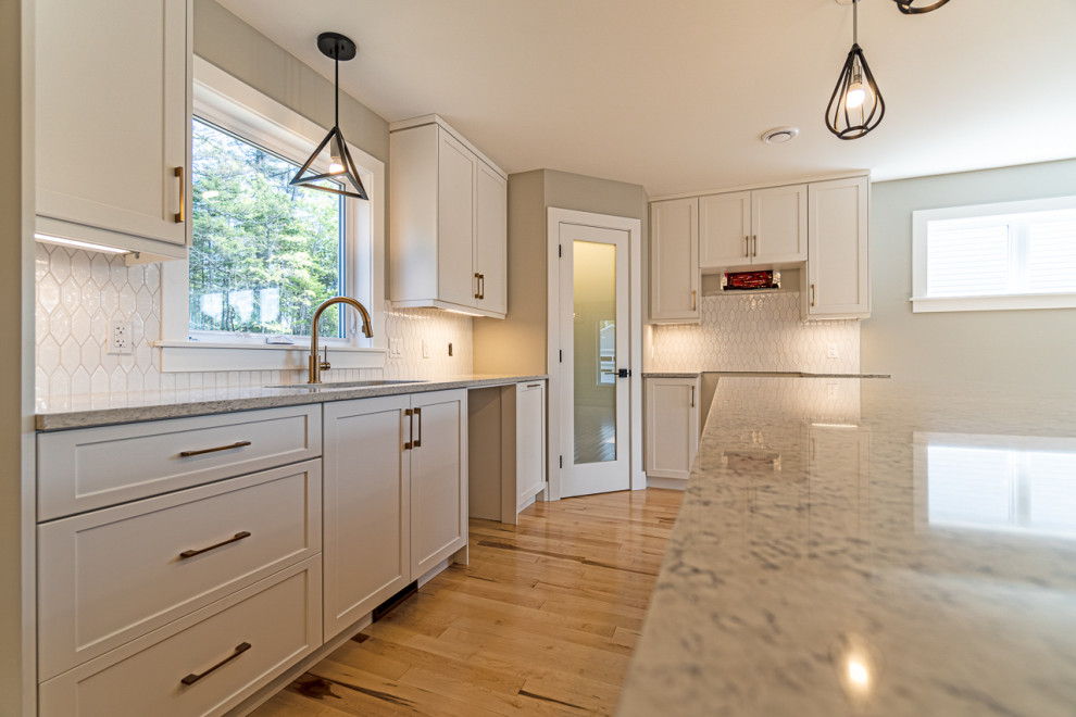 Mid-sized transitional light wood floor and beige floor eat-in kitchen photo with an undermount sink, shaker cabinets, white cabinets, granite countertops, white backsplash, ceramic backsplash, an island and gray countertops