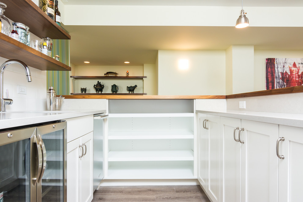 Inspiration for an expansive midcentury u-shaped seated home bar in Detroit with wood benchtops, white splashback, subway tile splashback, brown floor, vinyl floors, an undermount sink, shaker cabinets and white cabinets.