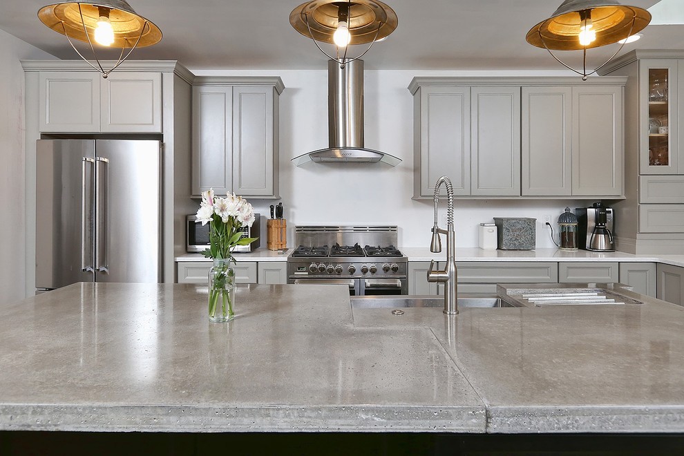 Inspiration for a mid-sized industrial l-shaped separate kitchen in Philadelphia with a farmhouse sink, recessed-panel cabinets, grey cabinets, concrete benchtops, stainless steel appliances, medium hardwood floors and with island.