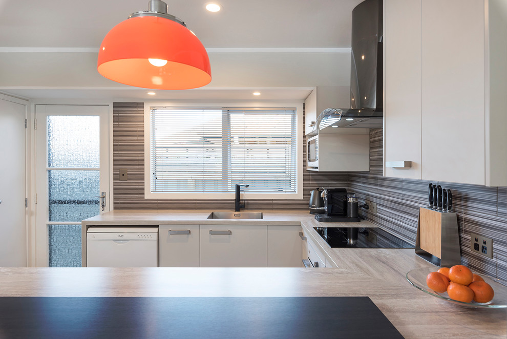 This is an example of a small contemporary u-shaped eat-in kitchen in Auckland with an undermount sink, flat-panel cabinets, beige cabinets, laminate benchtops, multi-coloured splashback, ceramic splashback, white appliances, ceramic floors, a peninsula and multi-coloured floor.