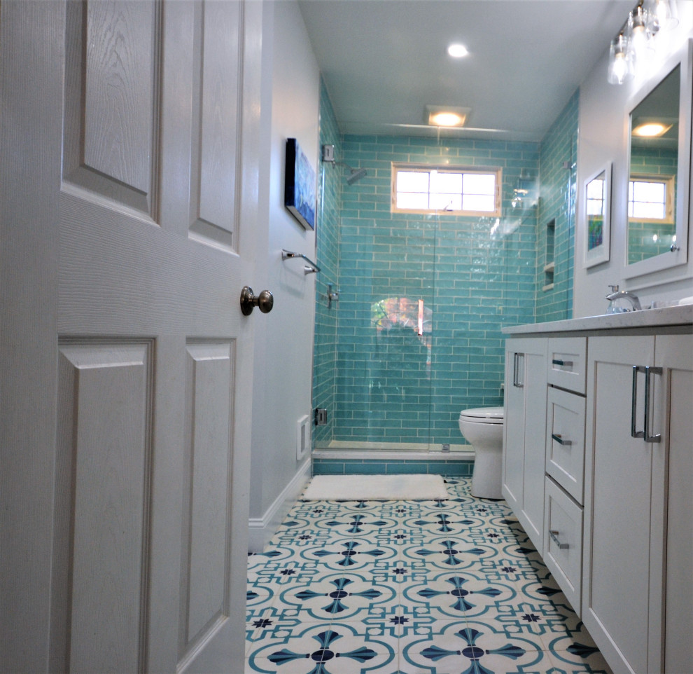 Идея дизайна: большая главная ванная комната в стиле неоклассика (современная классика) с фасадами в стиле шейкер, белыми фасадами, угловым душем, унитазом-моноблоком, зеленой плиткой, цементной плиткой, белыми стенами, полом из линолеума, врезной раковиной, столешницей из искусственного кварца, разноцветным полом, душем с распашными дверями, белой столешницей, нишей, тумбой под две раковины и встроенной тумбой