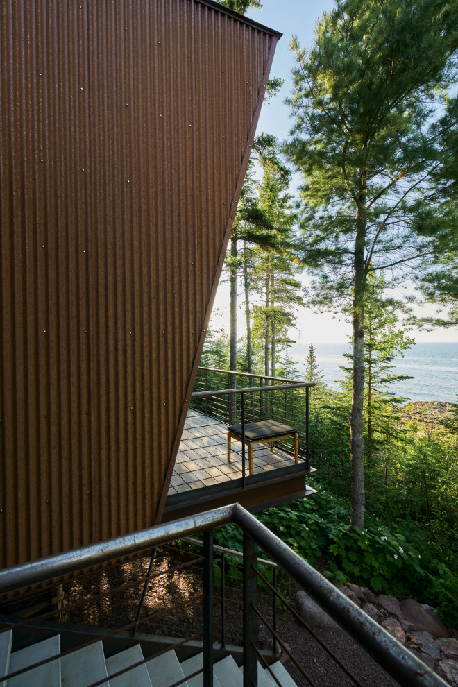 Example of a mountain style backyard metal railing deck design in Seattle with a roof extension
