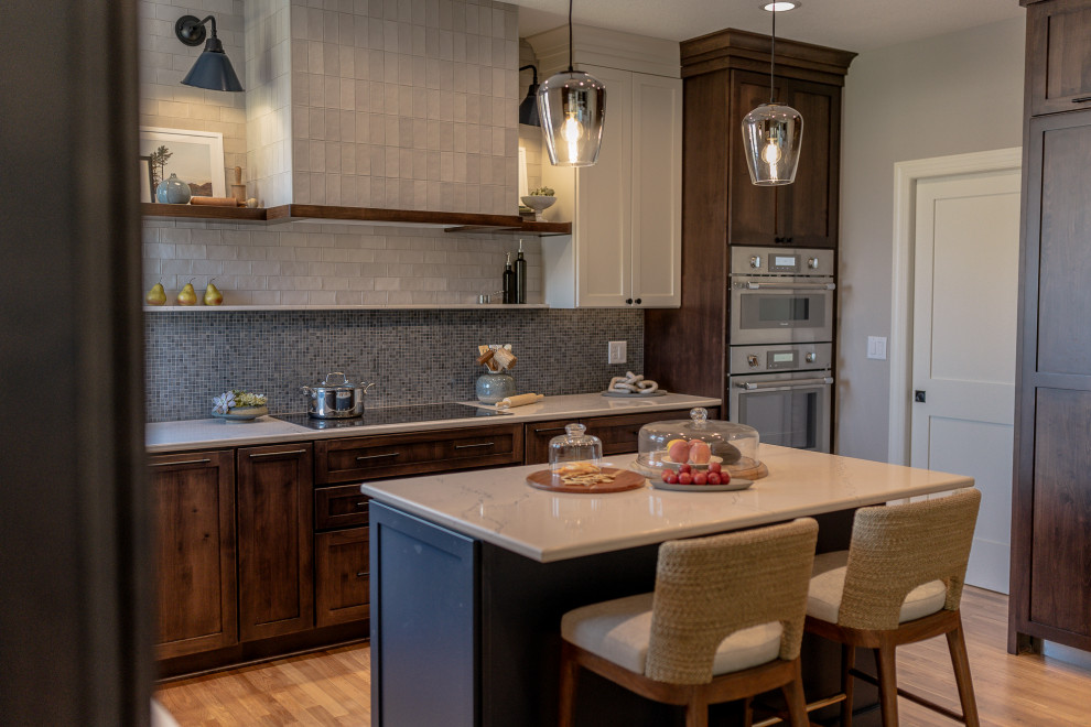 Inspiration for a mid-sized transitional l-shaped medium tone wood floor and brown floor eat-in kitchen remodel with an undermount sink, recessed-panel cabinets, dark wood cabinets, quartz countertops, blue backsplash, mosaic tile backsplash, stainless steel appliances, an island and white countertops