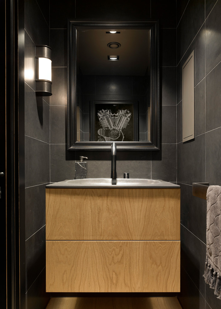 Inspiration for a contemporary powder room in Moscow with flat-panel cabinets, light wood cabinets, gray tile and an integrated sink.