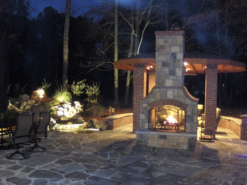 This is an example of a large traditional backyard patio in Atlanta with a fire feature, natural stone pavers and a gazebo/cabana.