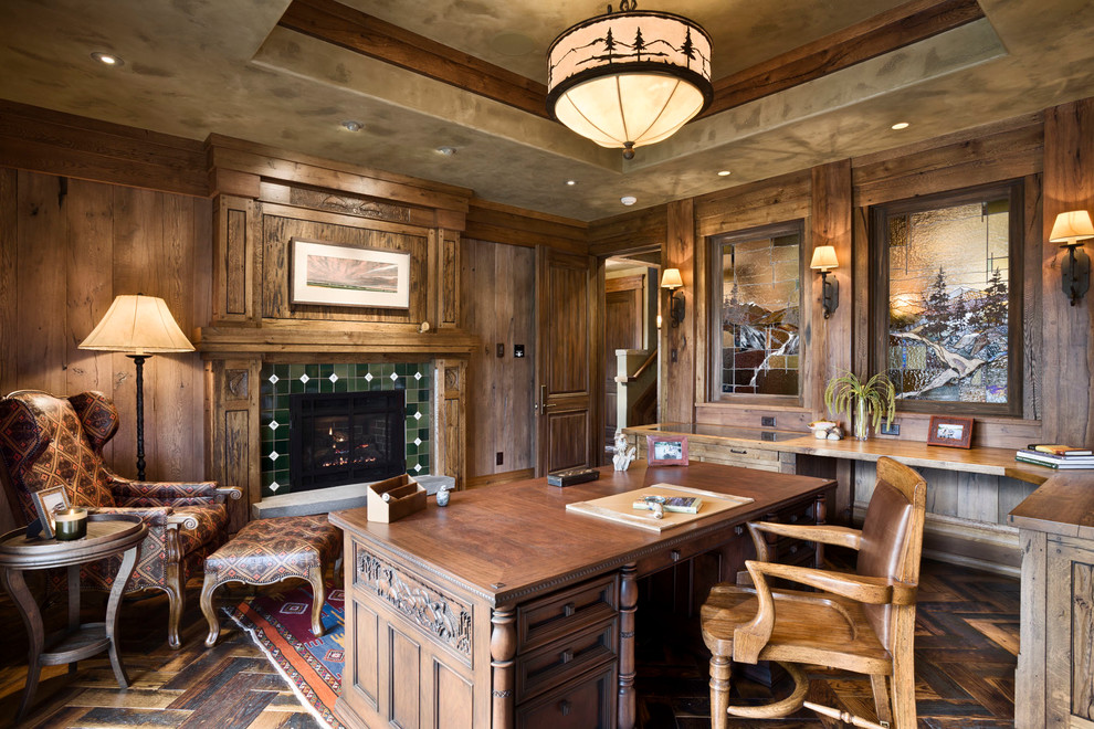 Large country home office in Other with dark hardwood floors, a standard fireplace, a tile fireplace surround and a freestanding desk.