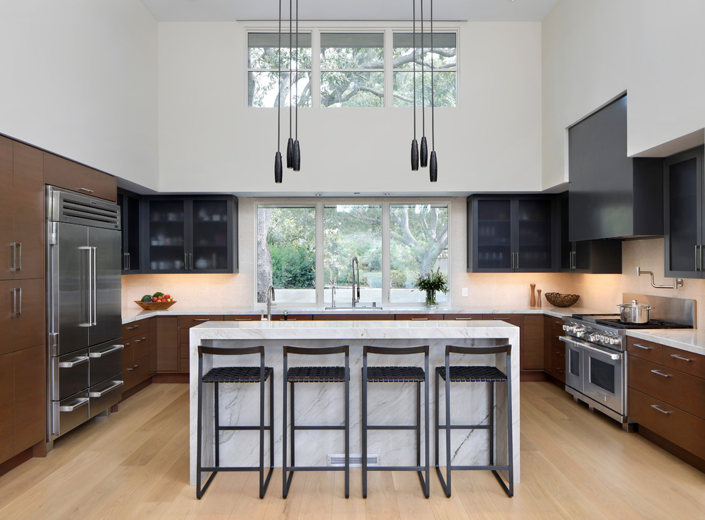 Photo of a contemporary u-shaped kitchen in San Francisco with an undermount sink, flat-panel cabinets, dark wood cabinets, window splashback, stainless steel appliances, light hardwood floors and with island.
