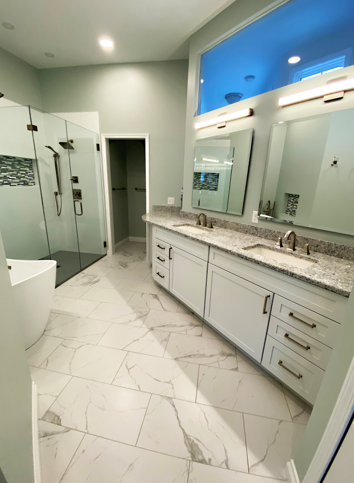 Photo of a large transitional master bathroom in Detroit with shaker cabinets, white cabinets, a freestanding tub, a corner shower, a two-piece toilet, white tile, ceramic tile, green walls, ceramic floors, an undermount sink, granite benchtops, white floor, a hinged shower door and brown benchtops.
