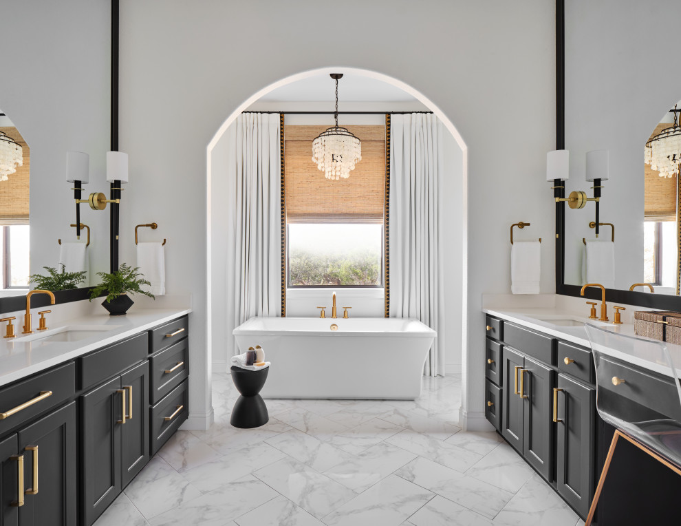 Inspiration for a large classic ensuite bathroom in Austin with shaker cabinets, black cabinets, a freestanding bath, a two-piece toilet, white tiles, porcelain tiles, white walls, porcelain flooring, a submerged sink, engineered stone worktops, grey floors, a hinged door, white worktops, an enclosed toilet, double sinks and a built in vanity unit.