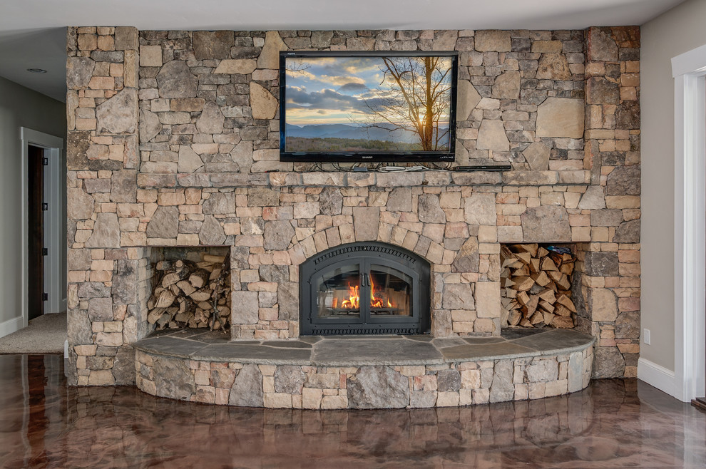 Photo of a large arts and crafts walk-out basement in Other with beige walls, concrete floors, a wood stove and a stone fireplace surround.