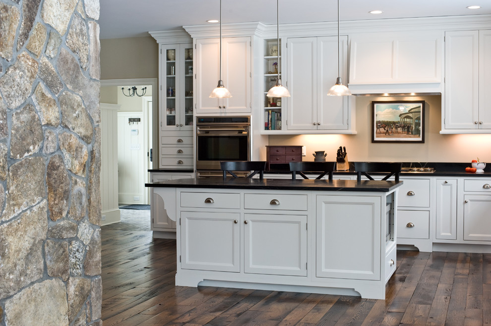 Traditional kitchen in Boston with a farmhouse sink, glass-front cabinets, white cabinets, soapstone benchtops, stainless steel appliances, medium hardwood floors and with island.