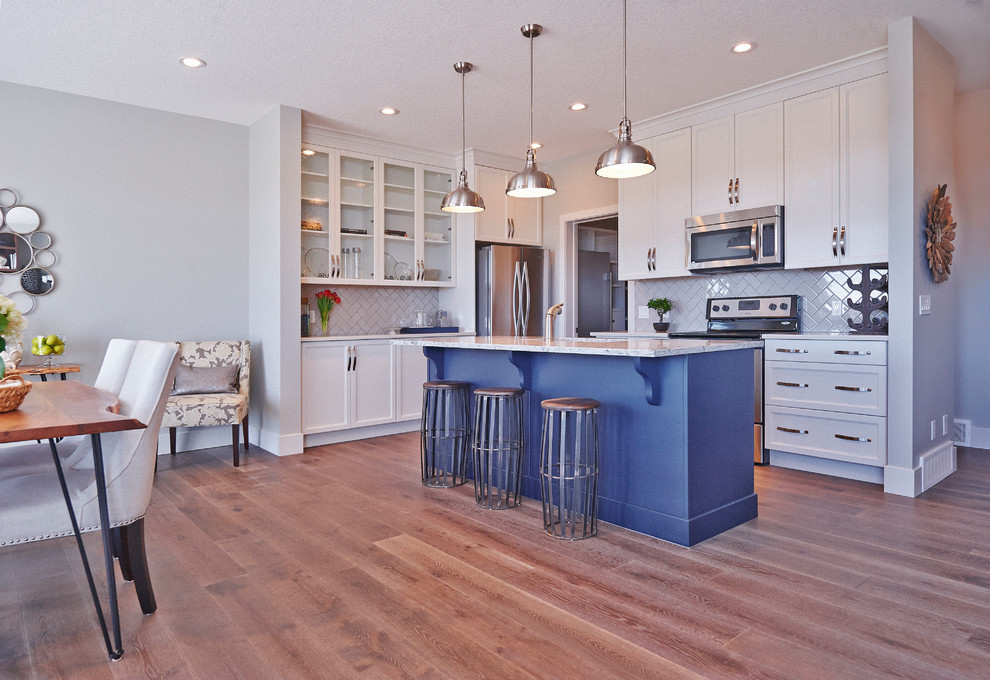 Design ideas for a transitional l-shaped eat-in kitchen in Calgary with a double-bowl sink, shaker cabinets, blue cabinets, quartzite benchtops, grey splashback, ceramic splashback, stainless steel appliances, medium hardwood floors and with island.