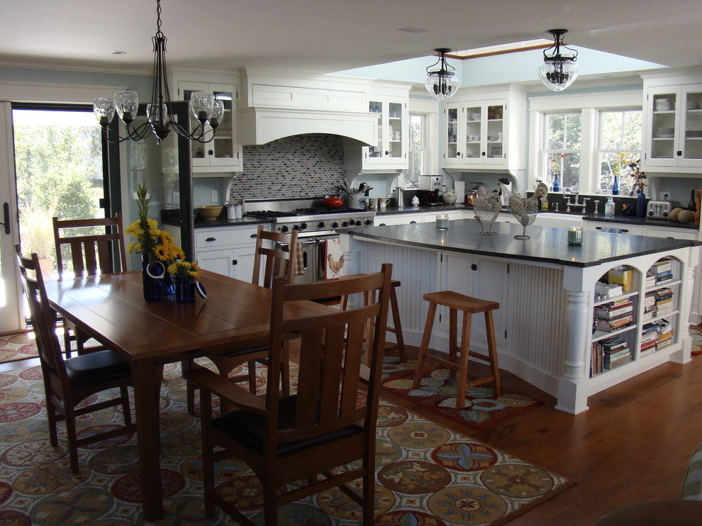 Photo of a mid-sized traditional l-shaped open plan kitchen in Portland Maine with a farmhouse sink, beaded inset cabinets, white cabinets, granite benchtops, multi-coloured splashback, glass tile splashback, stainless steel appliances, medium hardwood floors and with island.