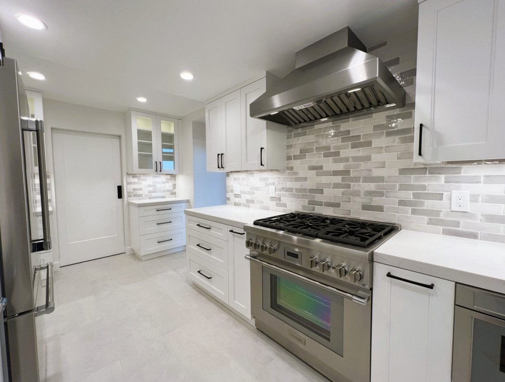 This is an example of a medium sized classic u-shaped enclosed kitchen in San Francisco with a single-bowl sink, recessed-panel cabinets, white cabinets, engineered stone countertops, grey splashback, ceramic splashback, stainless steel appliances, porcelain flooring and white worktops.