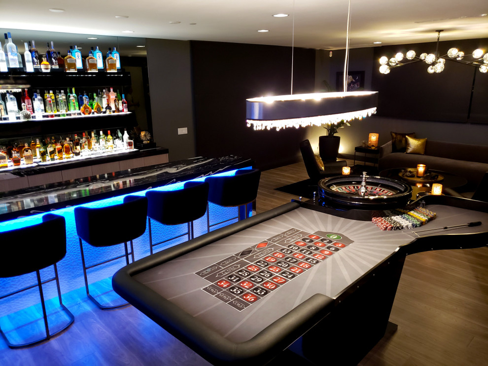 This is an example of a large modern galley seated home bar in Las Vegas with a drop-in sink, flat-panel cabinets, grey cabinets, marble benchtops, grey splashback, mirror splashback, porcelain floors, grey floor and multi-coloured benchtop.