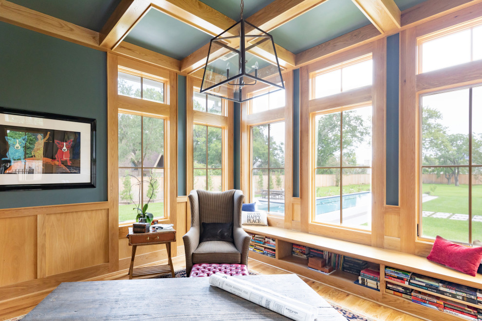 Large country home office in Houston with a library, blue walls, light hardwood floors, a standard fireplace, a brick fireplace surround, a freestanding desk and beige floor.