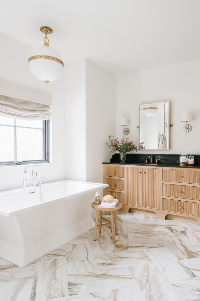 Стильный дизайн: большая главная ванная комната в стиле неоклассика (современная классика) с светлыми деревянными фасадами, отдельно стоящей ванной, двойным душем, унитазом-моноблоком, белой плиткой, белыми стенами, мраморным полом, накладной раковиной, столешницей из гранита, разноцветным полом, душем с распашными дверями, черной столешницей, сиденьем для душа, тумбой под две раковины, встроенной тумбой и плоскими фасадами - последний тренд