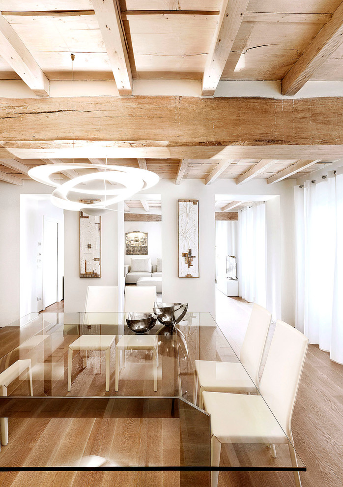 Contemporary dining room in Milan with white walls and medium hardwood floors.