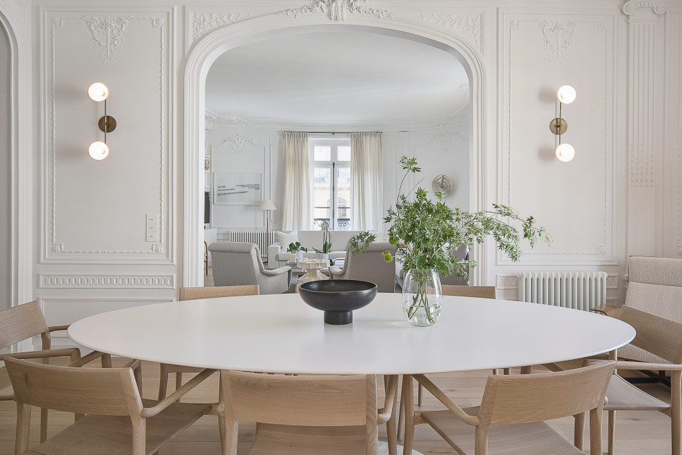 Inspiration pour une grande salle à manger design avec un mur blanc, parquet clair et boiseries.