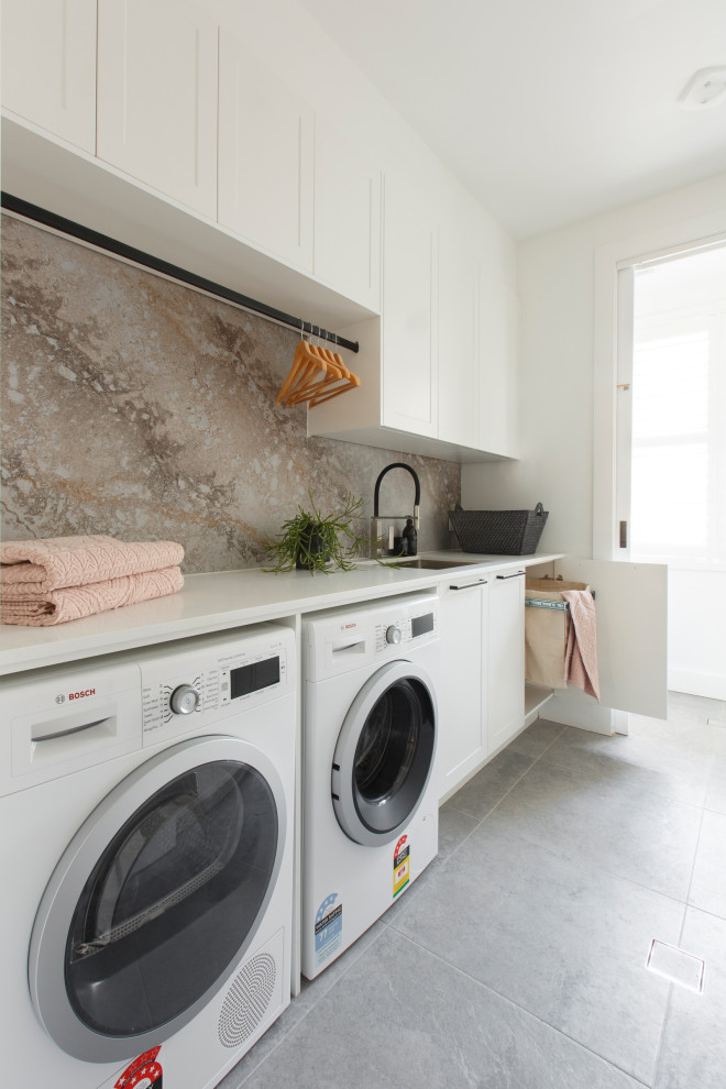 Example of a trendy single-wall gray floor laundry room design in Los Angeles with an undermount sink, shaker cabinets, white cabinets, white walls, a side-by-side washer/dryer and white countertops