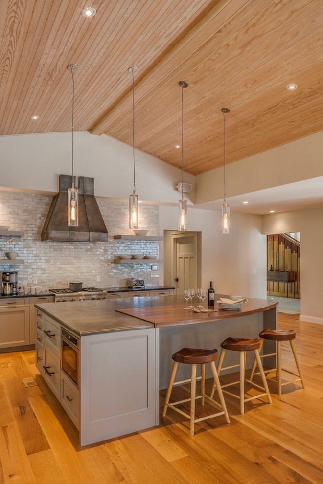 Design ideas for an expansive modern l-shaped open plan kitchen in Portland Maine with recessed-panel cabinets, grey cabinets, zinc benchtops, grey splashback, subway tile splashback, stainless steel appliances, medium hardwood floors and with island.