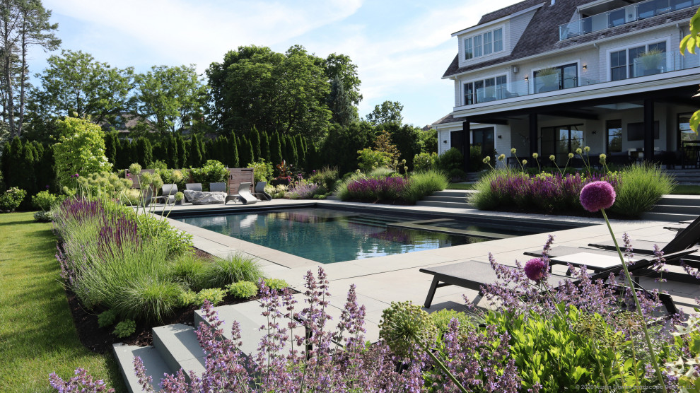 Photo of a large modern backyard rectangular lap pool in New York with with a pool and natural stone pavers.