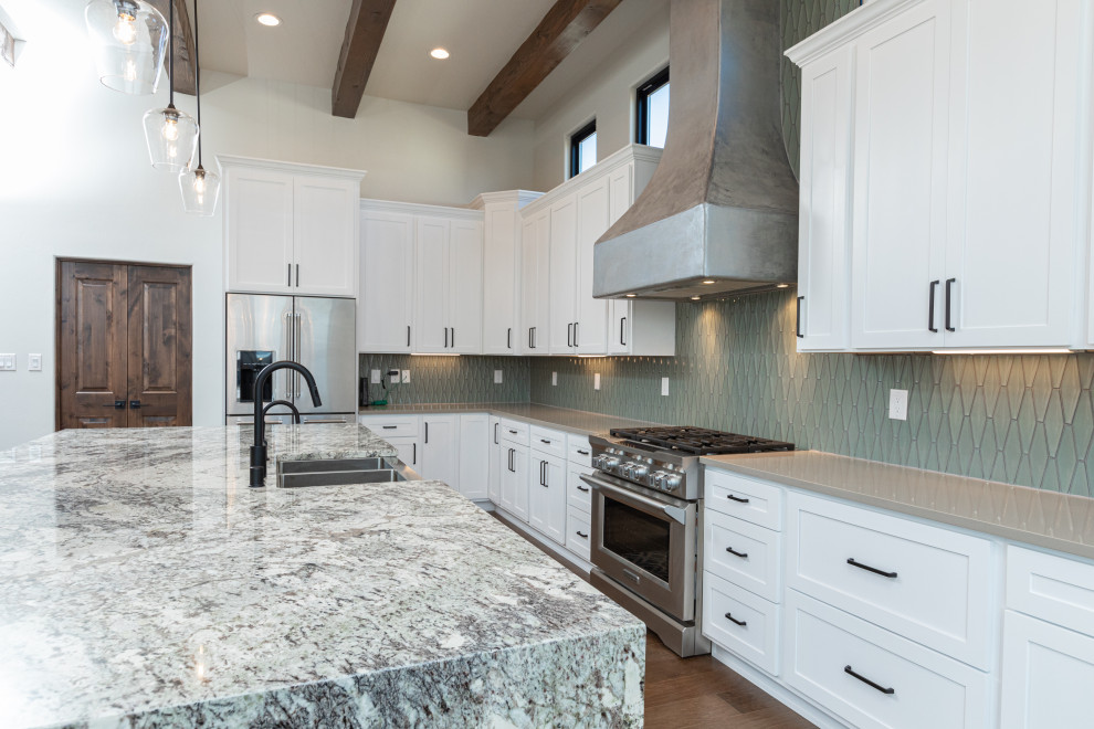 Design ideas for a large l-shaped eat-in kitchen in Albuquerque with a farmhouse sink, shaker cabinets, white cabinets, granite benchtops, green splashback, ceramic splashback, stainless steel appliances, medium hardwood floors, with island, brown floor and multi-coloured benchtop.