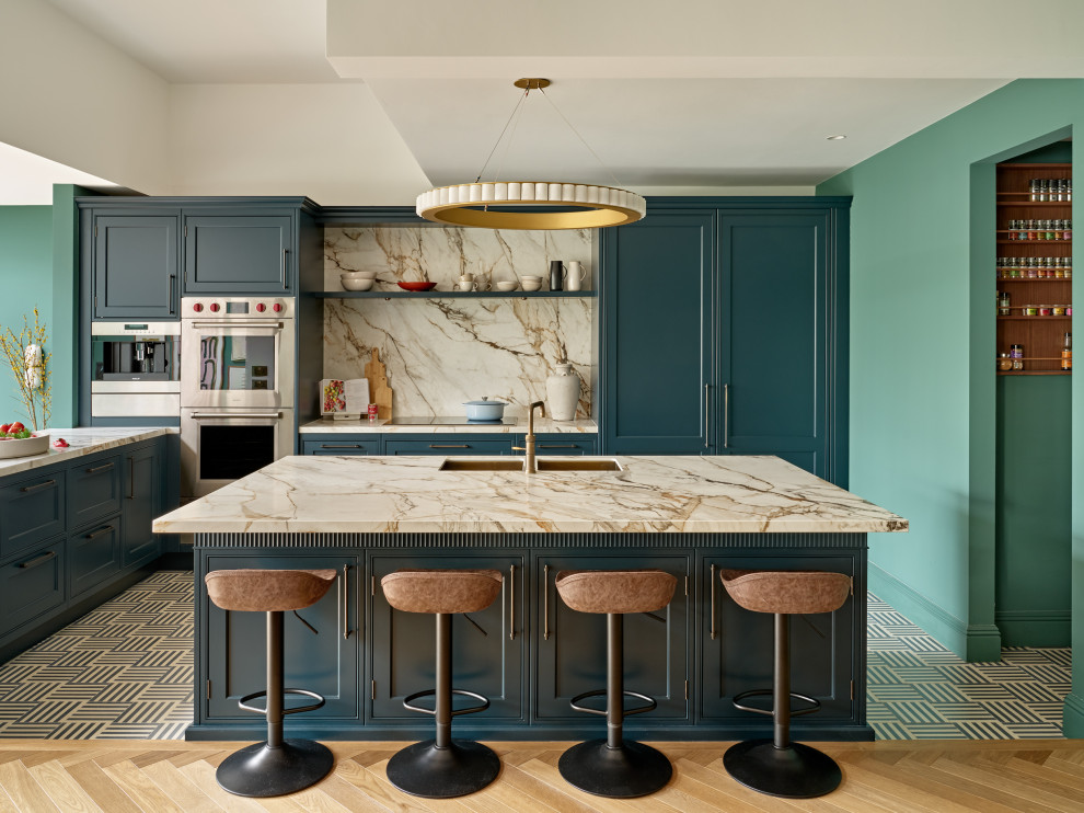 Inspiration for a large transitional kitchen in London with a drop-in sink, shaker cabinets, blue cabinets and marble benchtops.