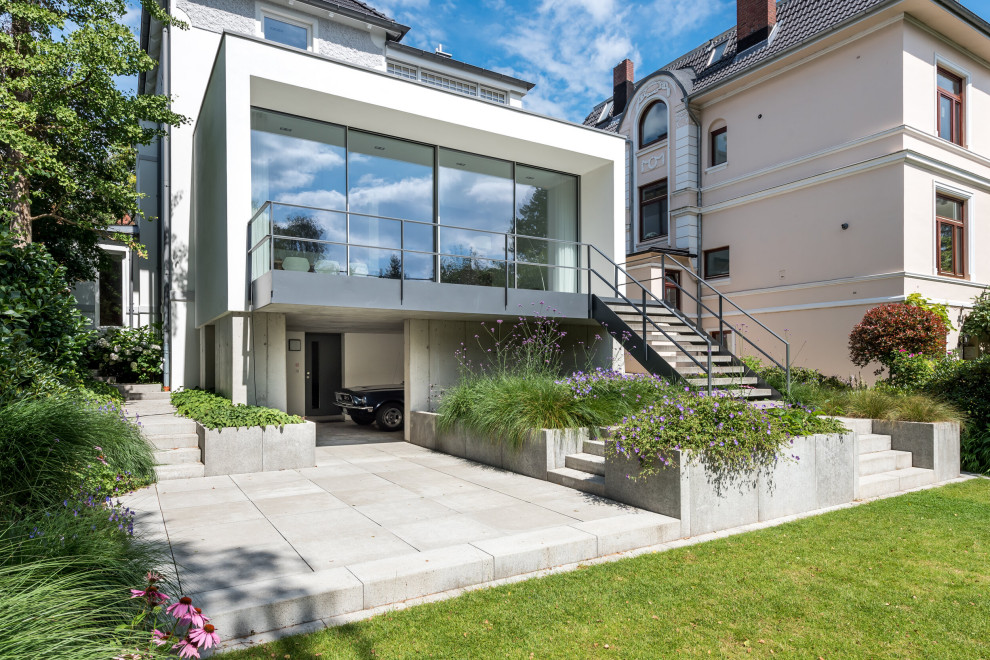 Photo of a mid-sized modern two-storey stucco white house exterior in Hamburg with a flat roof and a green roof.