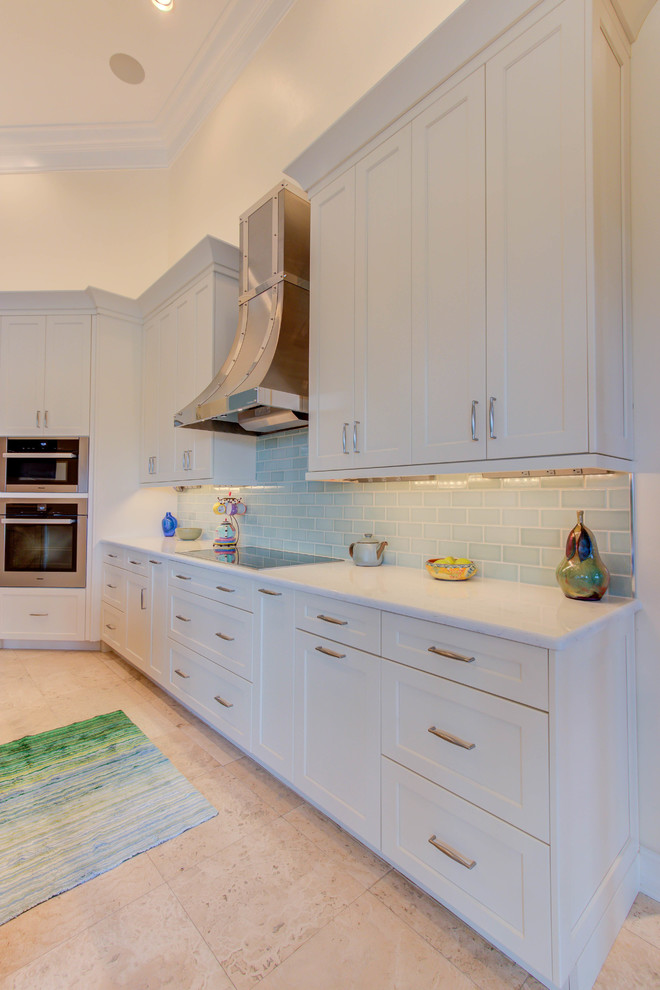 Example of a large transitional single-wall enclosed kitchen design with an undermount sink, flat-panel cabinets, white cabinets, quartz countertops, blue backsplash, stone tile backsplash, stainless steel appliances and an island