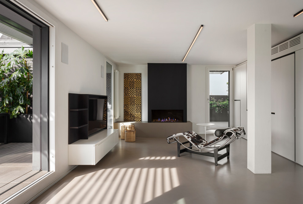 Inspiration for an expansive contemporary mezzanine games room in Milan with a reading nook, white walls, concrete flooring, a ribbon fireplace, a metal fireplace surround, a built-in media unit, grey floors and a drop ceiling.