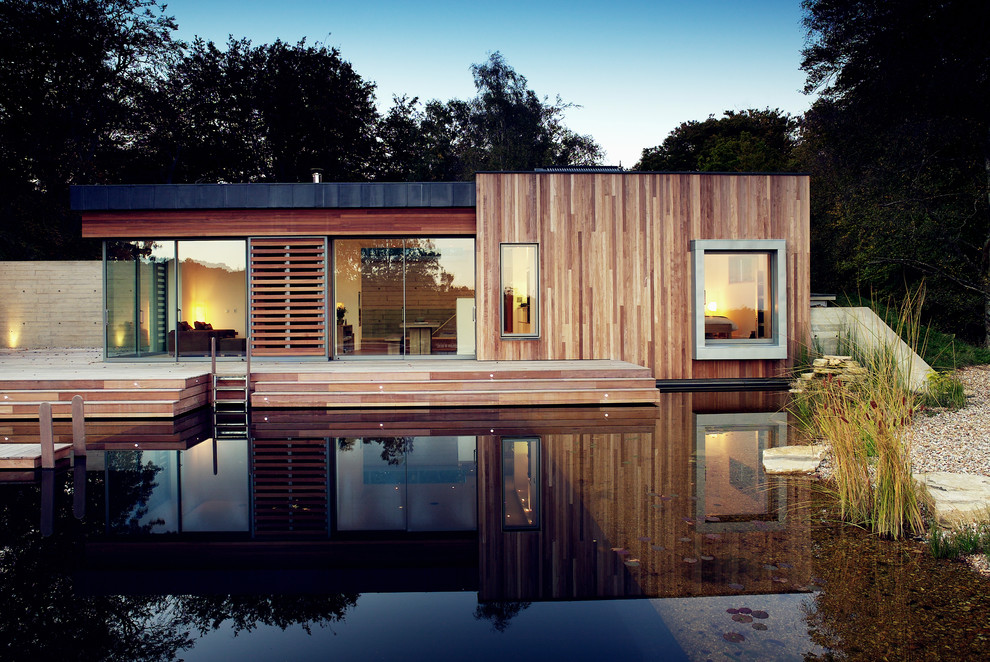 Photo of a mid-sized modern one-storey exterior in Hampshire with wood siding and a flat roof.