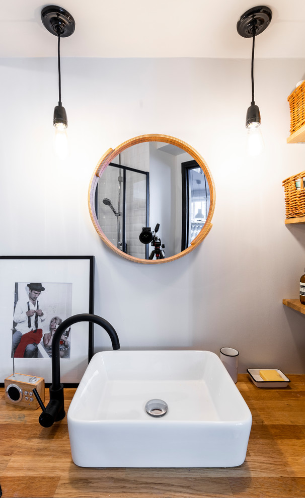 Photo of a small industrial 3/4 bathroom in Paris with a curbless shower, a wall-mount toilet, white tile, subway tile, white walls, cement tiles, a drop-in sink, wood benchtops, black floor, an open shower and beige benchtops.