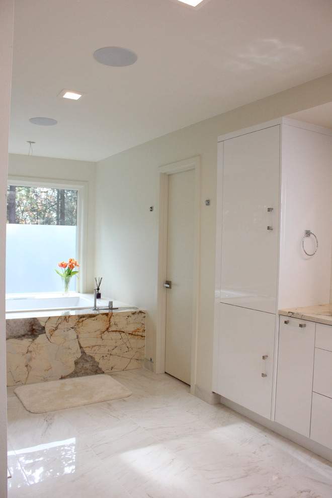 This is an example of a small modern master bathroom in Seattle with flat-panel cabinets, white cabinets, a drop-in tub, a corner shower, a one-piece toilet, white walls, porcelain floors, an undermount sink, white floor, a hinged shower door and beige benchtops.
