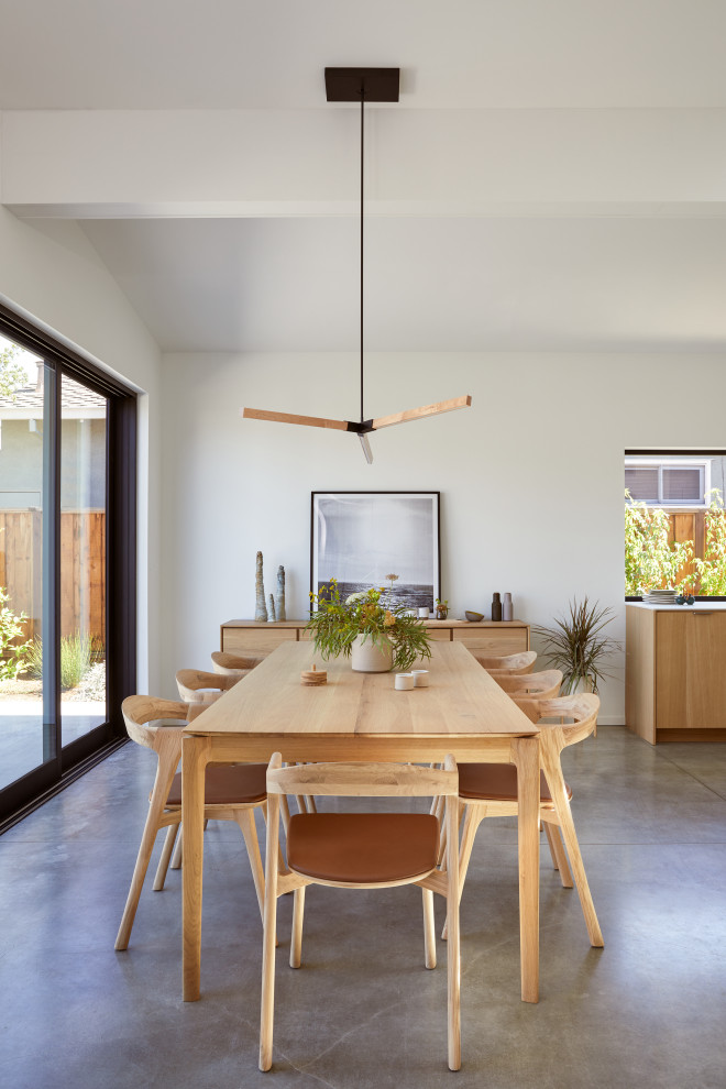 Foto de comedor minimalista de tamaño medio abierto sin chimenea con paredes blancas, suelo de cemento, suelo gris y vigas vistas