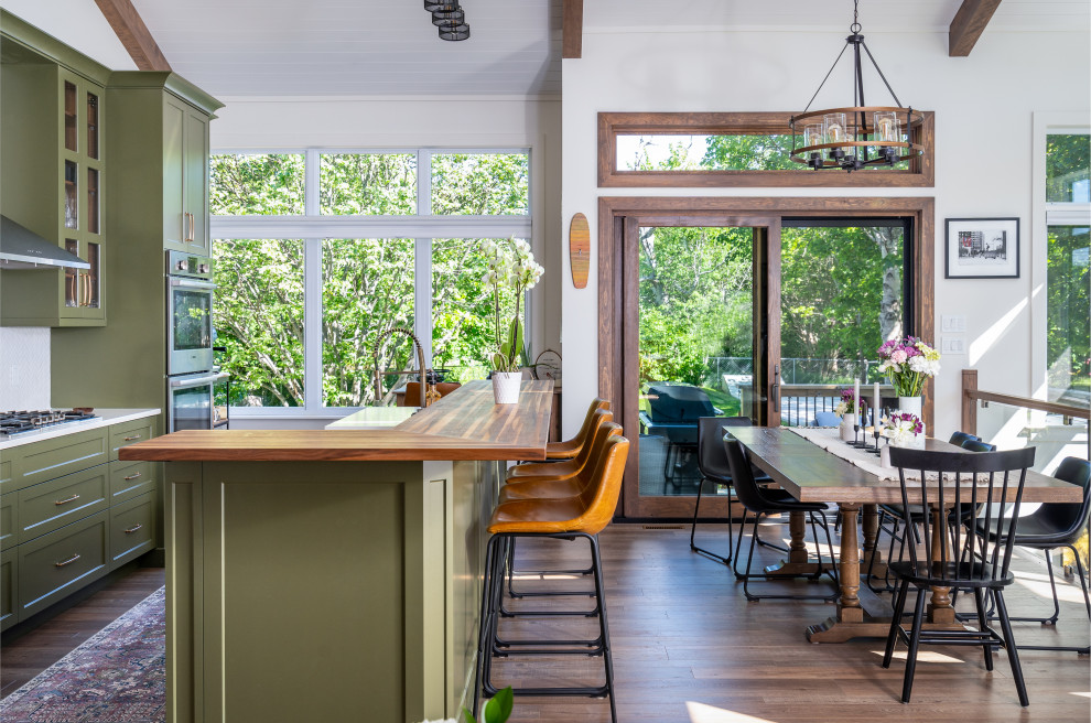 Mid-sized transitional l-shaped eat-in kitchen photo with an undermount sink, shaker cabinets, green cabinets, quartz countertops, white backsplash, ceramic backsplash, stainless steel appliances, an island and white countertops