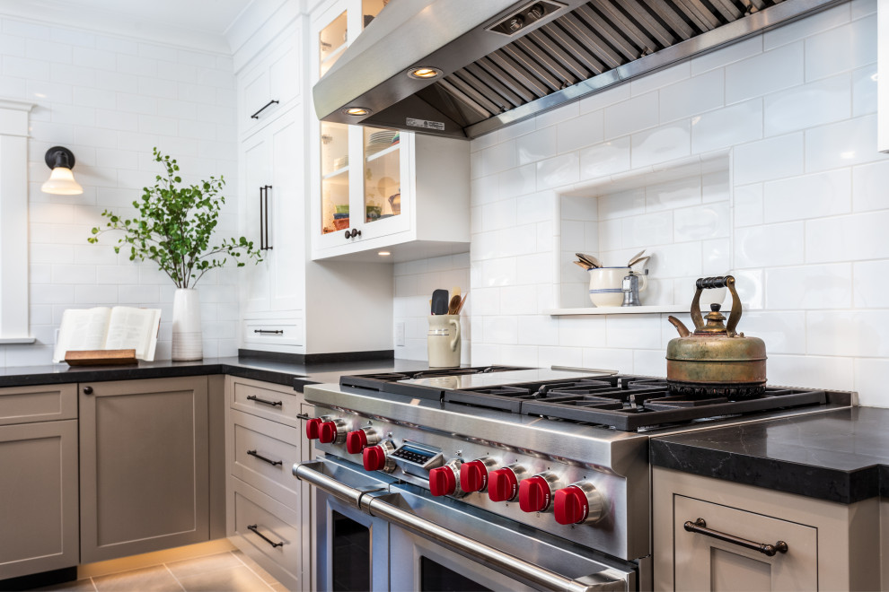 This is an example of a mid-sized arts and crafts separate kitchen in Los Angeles with a farmhouse sink, white splashback, stainless steel appliances, with island, grey floor and white benchtop.