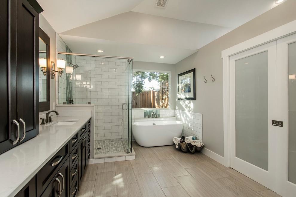 Design ideas for a mid-sized contemporary master bathroom in Los Angeles with shaker cabinets, dark wood cabinets, a curbless shower, a one-piece toilet, multi-coloured tile, porcelain tile, beige walls, plywood floors, an integrated sink, solid surface benchtops, beige floor, a sliding shower screen and white benchtops.