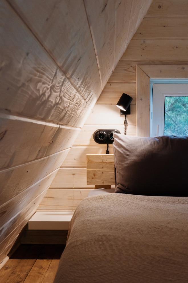 На фото: спальня на антресоли, на мансарде в скандинавском стиле с деревянным полом, деревянным потолком и деревянными стенами с