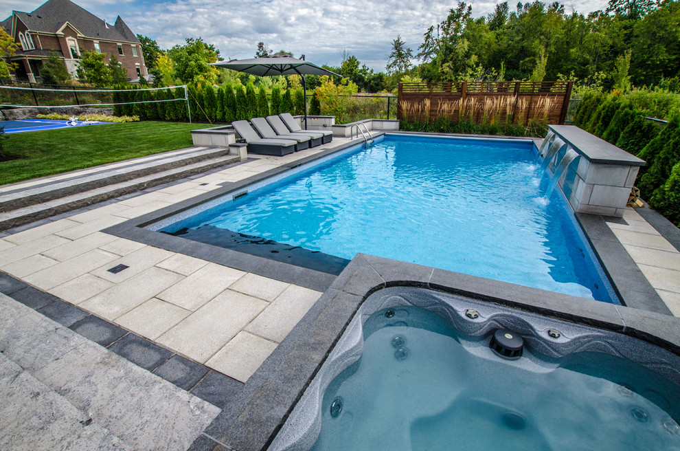 Design ideas for a large contemporary backyard pool in Toronto with natural stone pavers and a water feature.