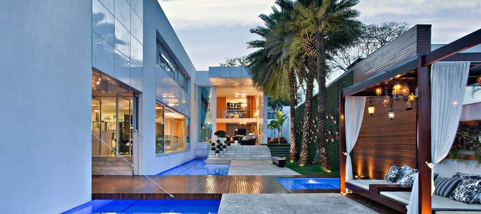 This is an example of a large contemporary two-storey stucco white exterior in Miami with a flat roof.
