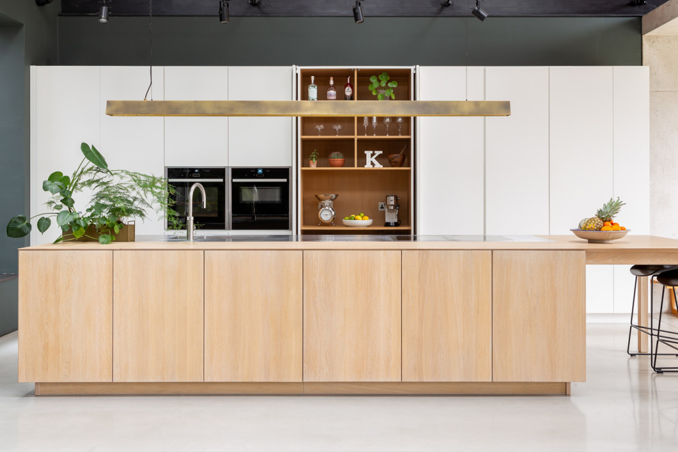Inspiration for an expansive scandinavian open plan kitchen in London with flat-panel cabinets, white cabinets, stainless steel benchtops, with island and multi-coloured benchtop.