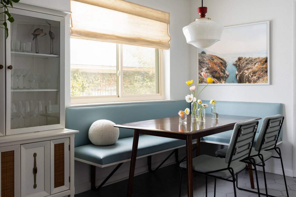 Cette image montre une salle à manger vintage avec une banquette d'angle, un mur blanc et un sol gris.