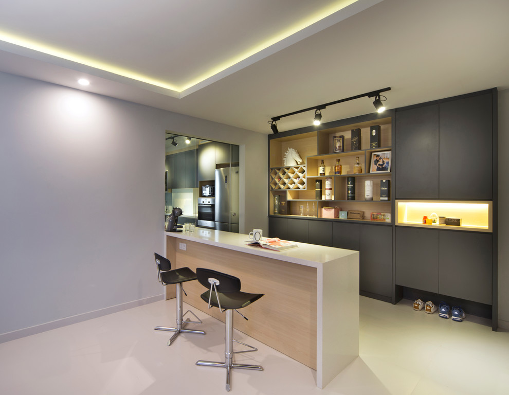 Photo of a contemporary galley seated home bar in Singapore with flat-panel cabinets, grey cabinets, beige floor and beige benchtop.
