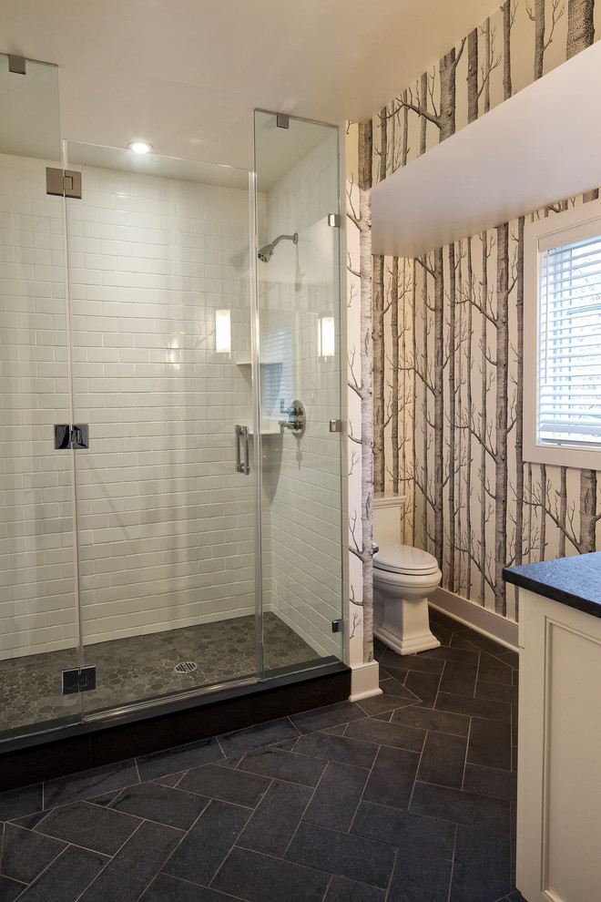 Photo of a traditional master bathroom in New York with beaded inset cabinets, white cabinets, an alcove shower, a two-piece toilet, white tile, white walls, slate floors, an undermount sink, soapstone benchtops, black floor, a hinged shower door and black benchtops.