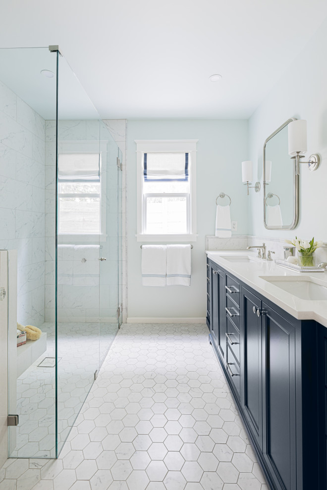 This is an example of a mid-sized transitional master bathroom in Los Angeles with blue cabinets, a curbless shower, marble, blue walls, porcelain floors, an undermount sink, engineered quartz benchtops, white floor, a hinged shower door, white benchtops, a shower seat, a double vanity, a built-in vanity, white tile and recessed-panel cabinets.
