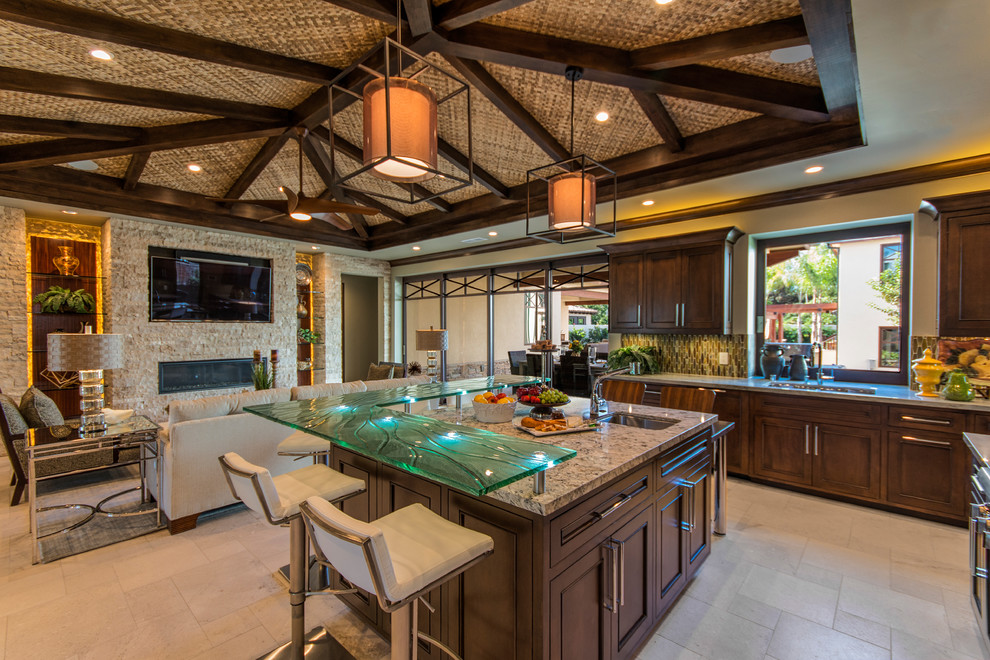 Inspiration for a tropical u-shaped open plan kitchen in San Diego with recessed-panel cabinets, dark wood cabinets, granite benchtops, green splashback, glass tile splashback, travertine floors and with island.