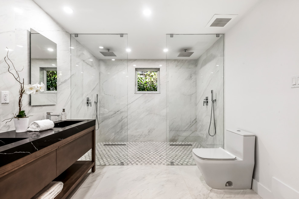 Photo of a large contemporary master bathroom in Miami with dark wood cabinets, a one-piece toilet, marble, white walls, marble floors, marble benchtops, white floor, an open shower, black benchtops, a double vanity, a freestanding vanity, black and white tile, a console sink and a curbless shower.